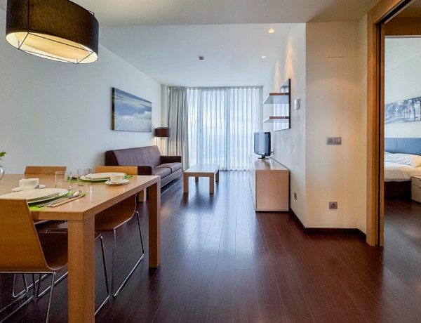 Comedor y sala con mesa, sof&aacute;s, minibar y puerta a dormitorio, interior moderno