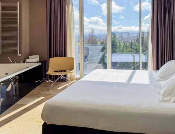 Habitaci&oacute;n de hotel con cama doble, ba&ntilde;o y ventana al paisaje.
