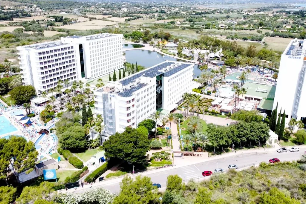 Vista a&eacute;rea de un hotel con piscinas, jardines y paneles solares, en un valle.
