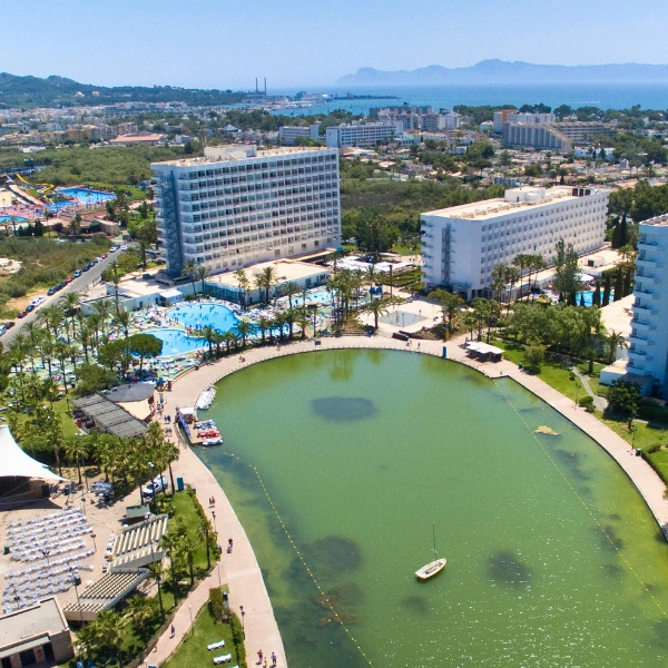 Hotel con piscina y laguna verde al fondo, vista panor&aacute;mica costera