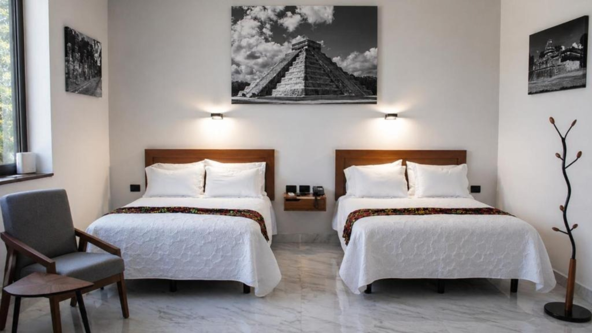 Dormitorio moderno con dos camas, l&aacute;mparas y cuadros en blanco y negro
