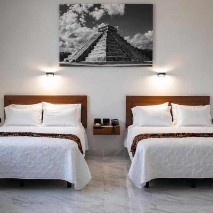 Dos camas dobles en una habitaci&oacute;n con cuadro de la pir&aacute;mide de Chich&eacute;n Itz&aacute;