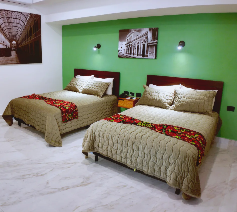 Dormitorio con dos camas, ropa de cama beige y pared verde.