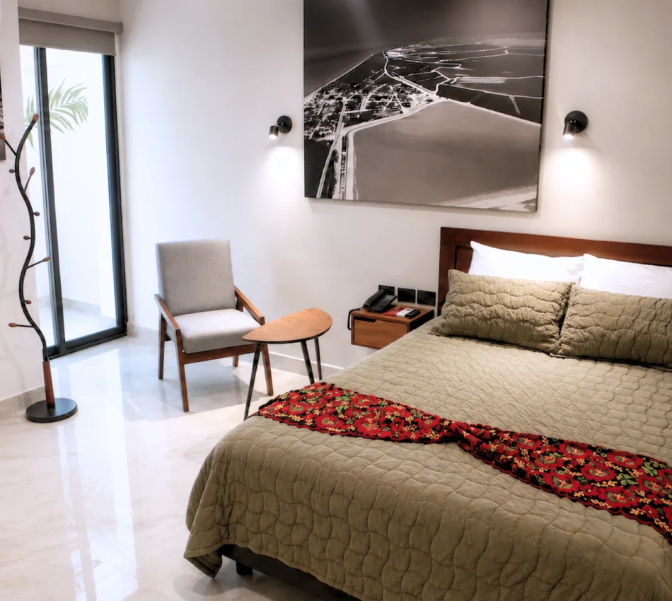 Dormitorio moderno con cama, sill&oacute;n y cuadro urbano en la pared