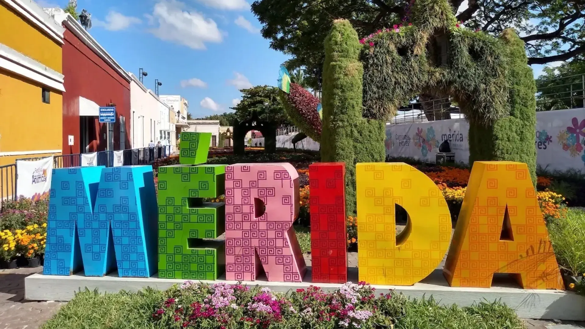 Letras gigantes de colores con flores y &aacute;rboles en un jard&iacute;n del centro.