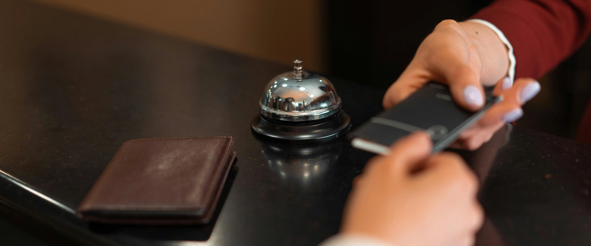 Recepcionista usando el timbre/contestador de hotel con campana sobre la mesa