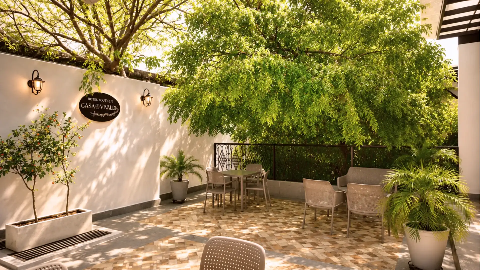 Patio de hotel con jard&iacute;n verde, sillas y letrero &ldquo;Casa Vivaldi&rdquo;.