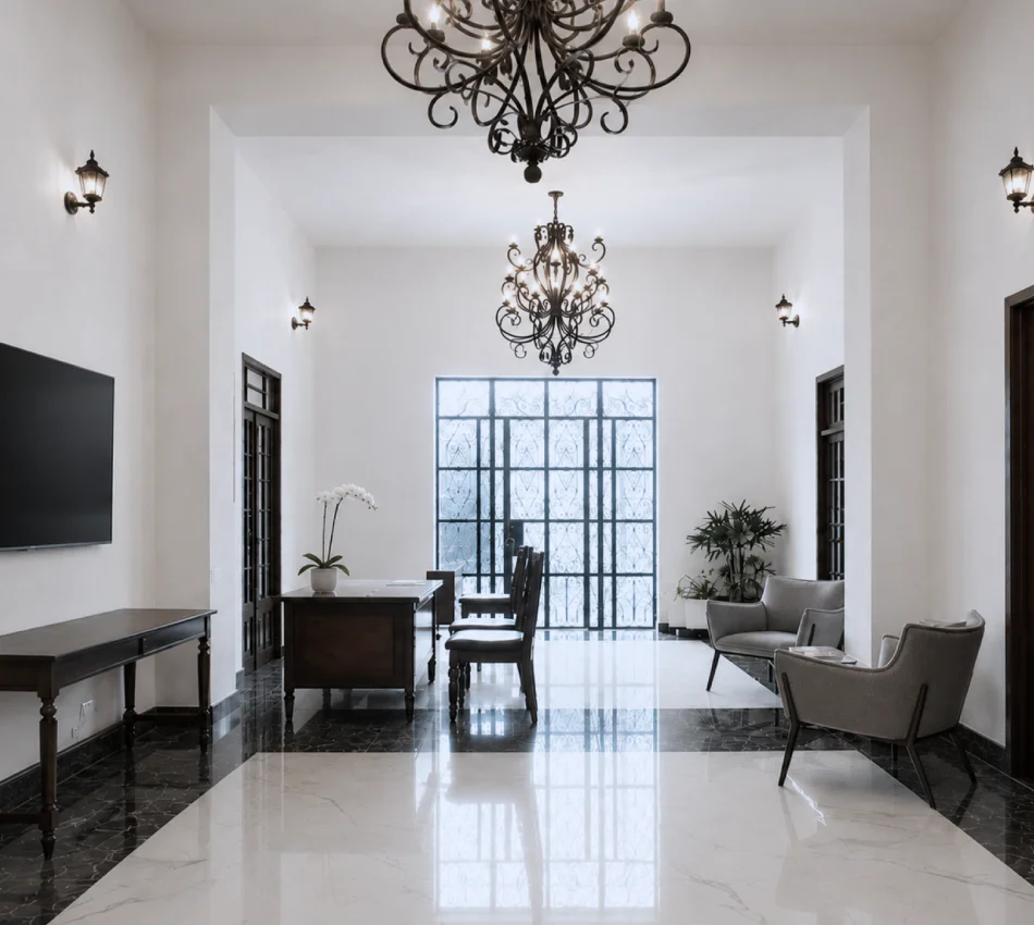 Sala elegante con dos l&aacute;mparas de ara&ntilde;a, muebles y ventana enmarcada de hierro