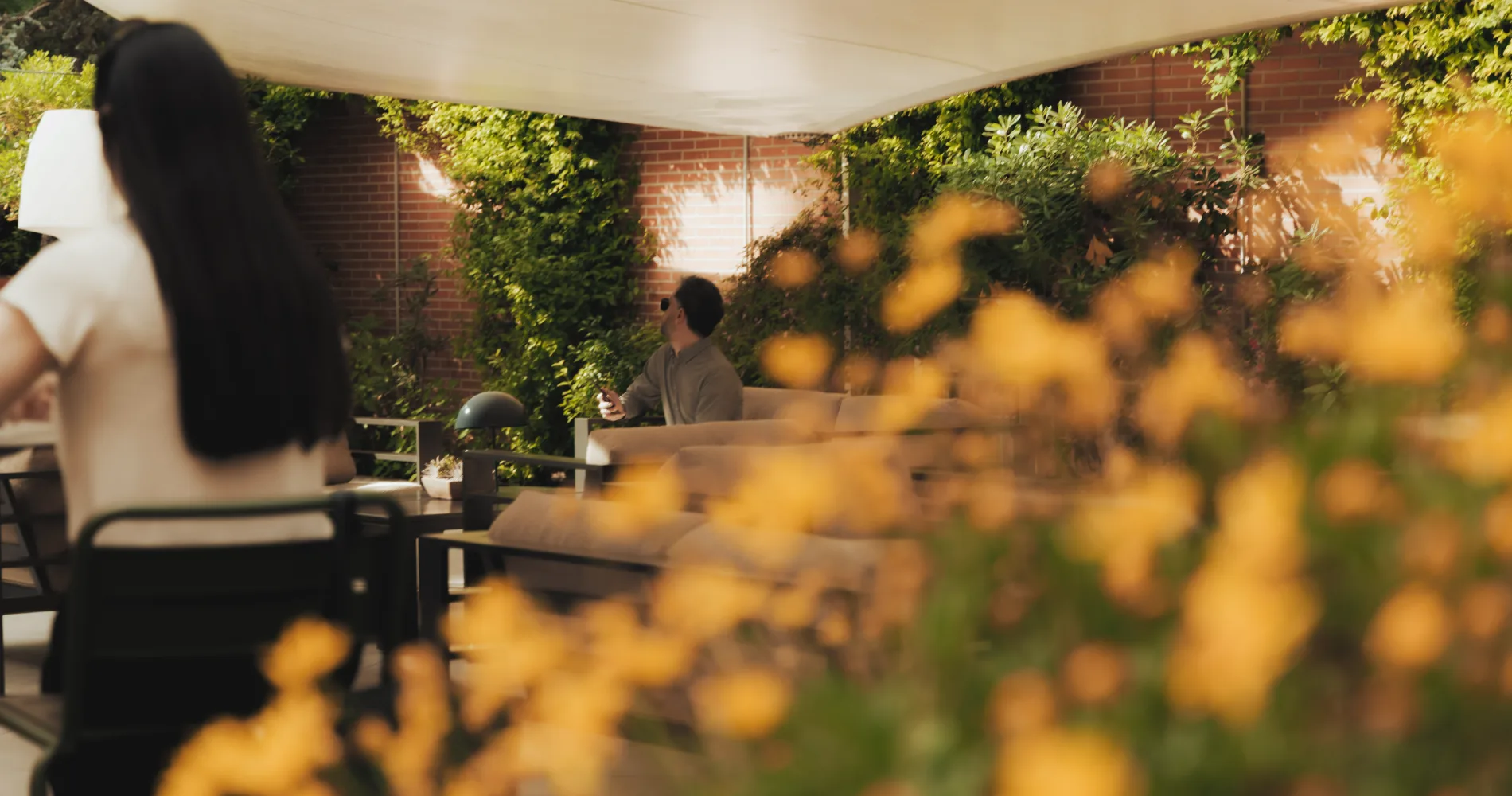 Terraza con vegetaci&oacute;n, mesa y personas conversando al aire libre