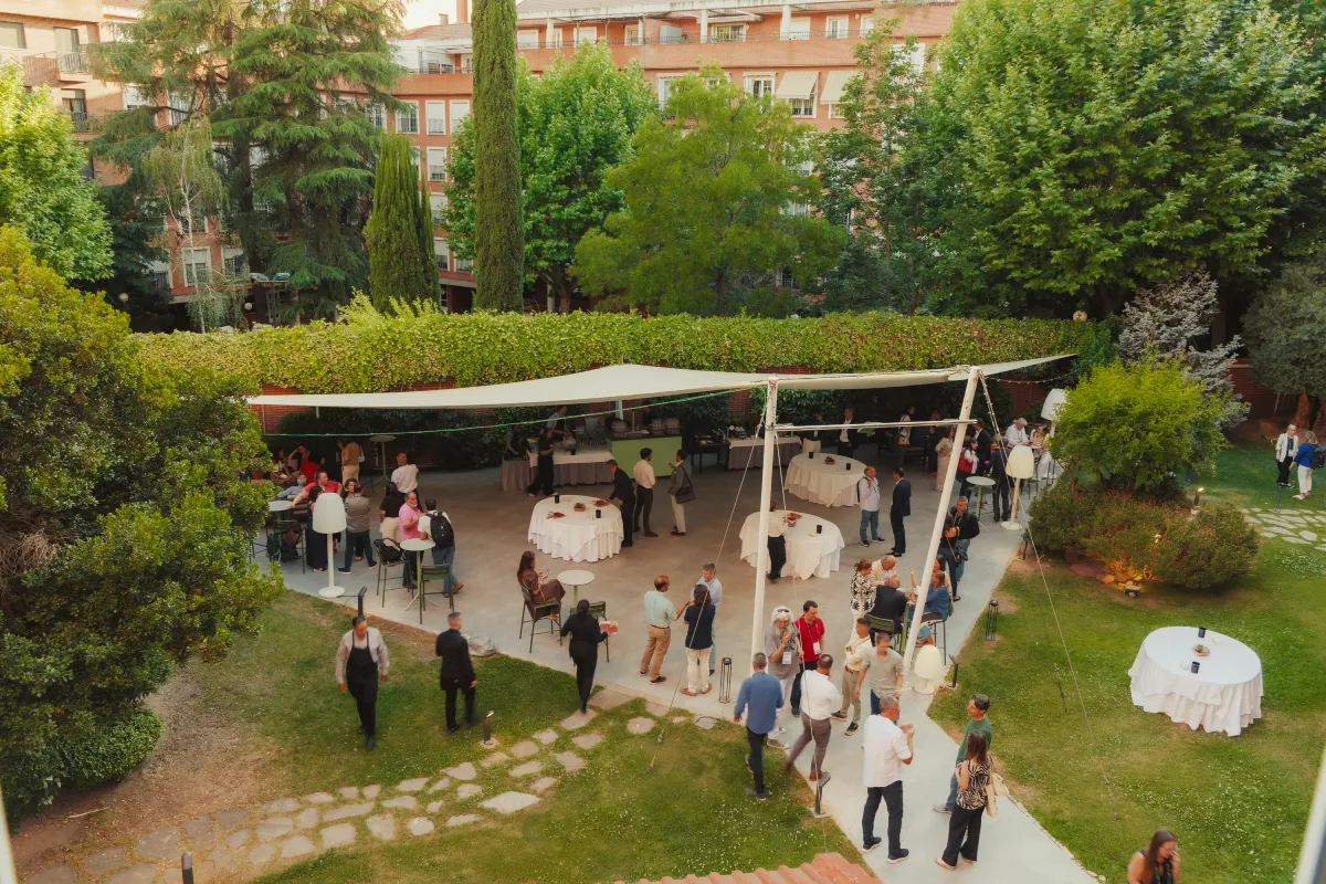 Cóctel al aire libre bajo carpa en jardín con invitados en evento.