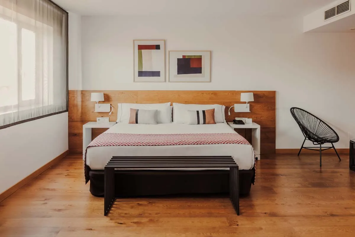 Dormitorio moderno con cama doble, cabecero de madera y silla negra decorativa