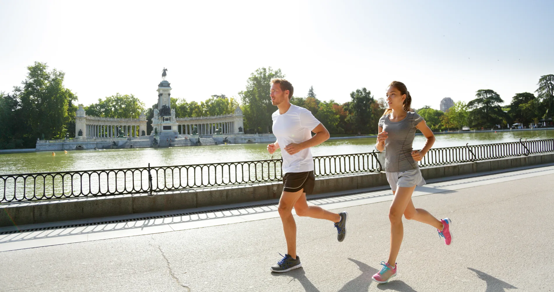 Dos personas corriendo junto al lago y un monumento en un parque