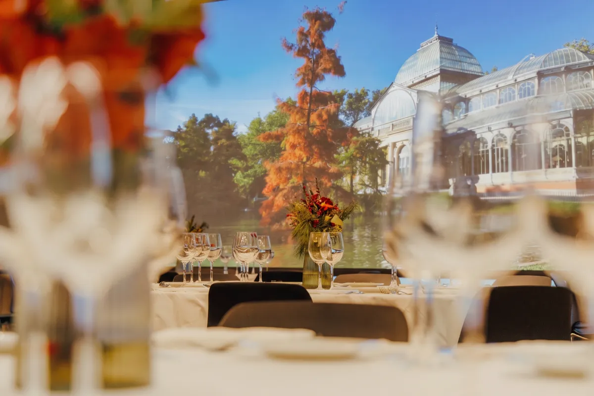 Mesa con copas y ramo de flores frente al Palacio de Cristal al aire libre