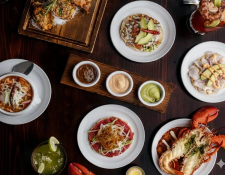Mesa con platos de comida: tacos, ensalada, pollo y postre, con bebidas.