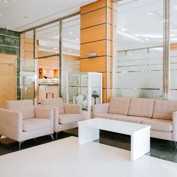 Sala moderna con sof&aacute;s beige y mesa blanca en un espacio interior amplio