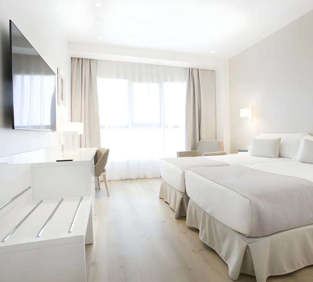 Dormitorio moderno con dos camas blancas, cortinas y luz natural