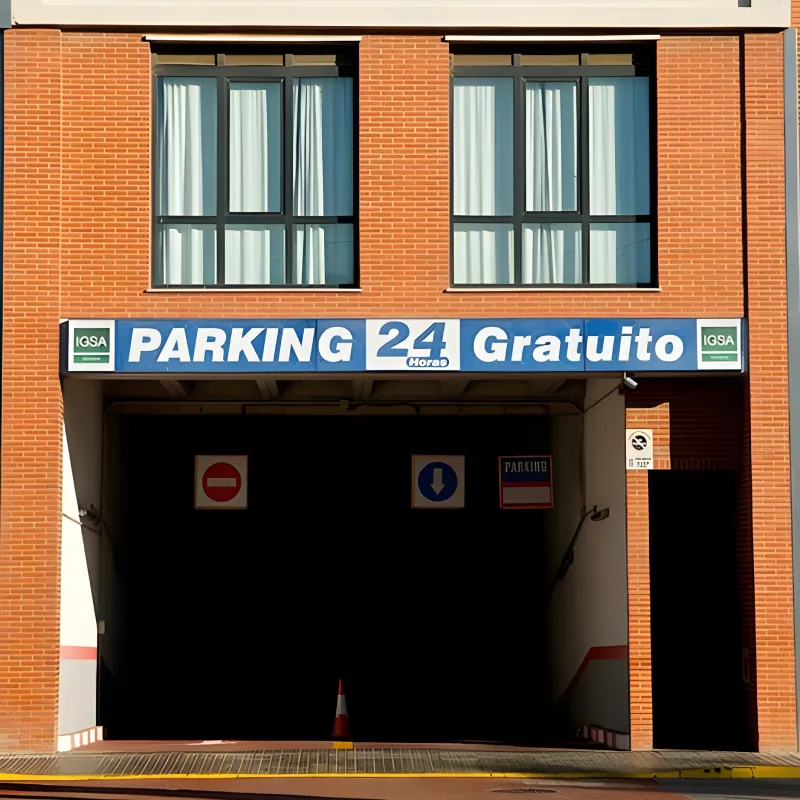 Entrada de parking con letrero &ldquo;Parking 24 horas gratuito&rdquo; en edificio de ladrillo