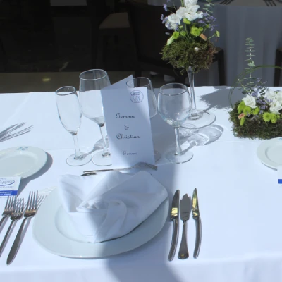 Mesa de banquete con copas, platos, servilletas y decoraci&oacute;n floral.