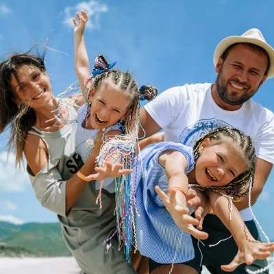 Familia sonriente con trajes y ni&ntilde;a haciendo la se&ntilde;al de &ldquo;rock&rdquo; al aire libre