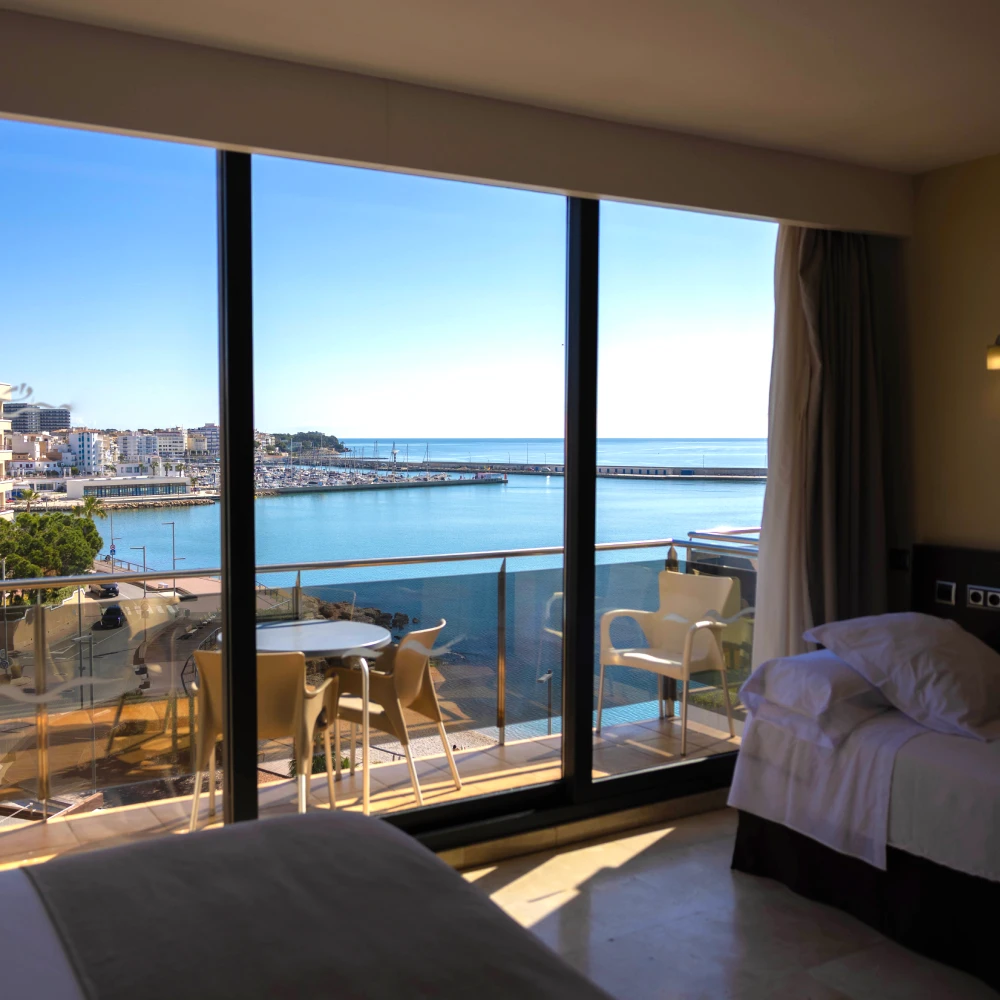 Habitaci&oacute;n con vista al puerto y al mar, con mesas y sillas en terraza