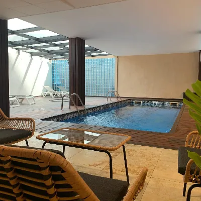 Piscina cubierta con camastros y reja de seguridad en un hotel.
