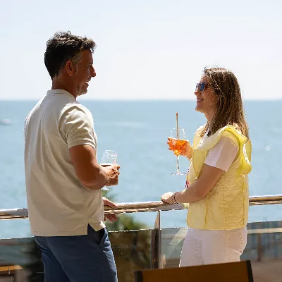 Pareja brindando con bebidas junto al mar en un crucero