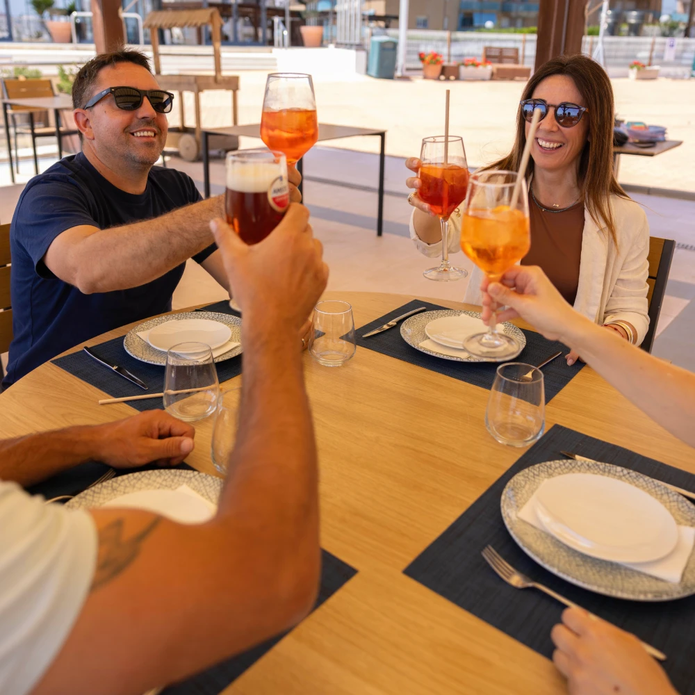 Brindis en terraza: tres personas con copas de aperitivo color &aacute;mbar
