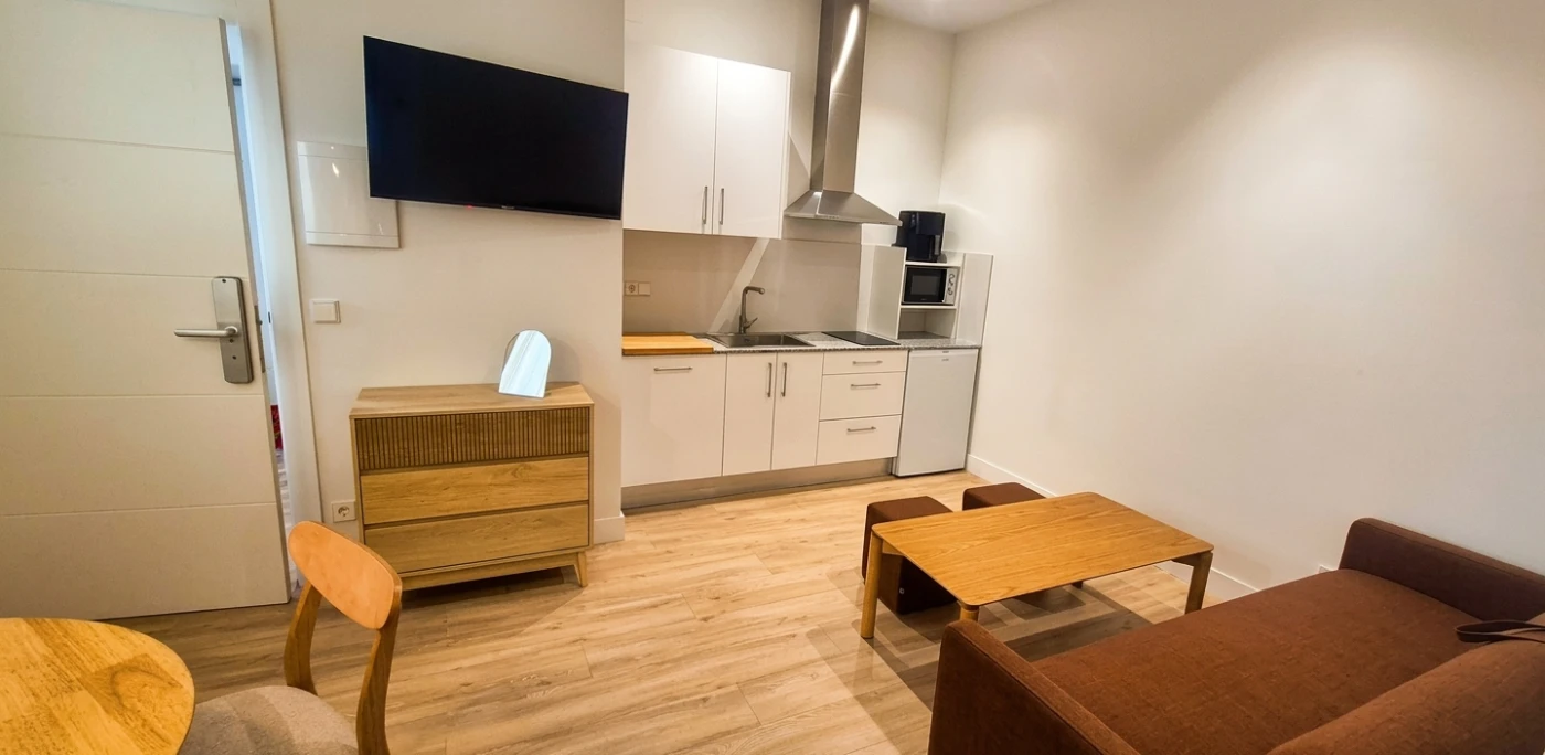 Cocina equipada con encimera, microondas y mesa con sillas en comedor.