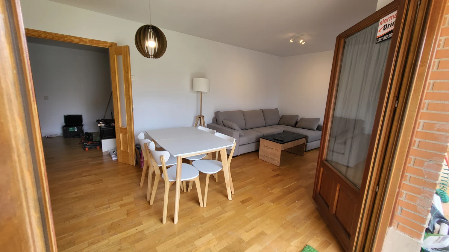 Comedor con mesa blanca, sofá gris y ventana con cortinas, sala de estar