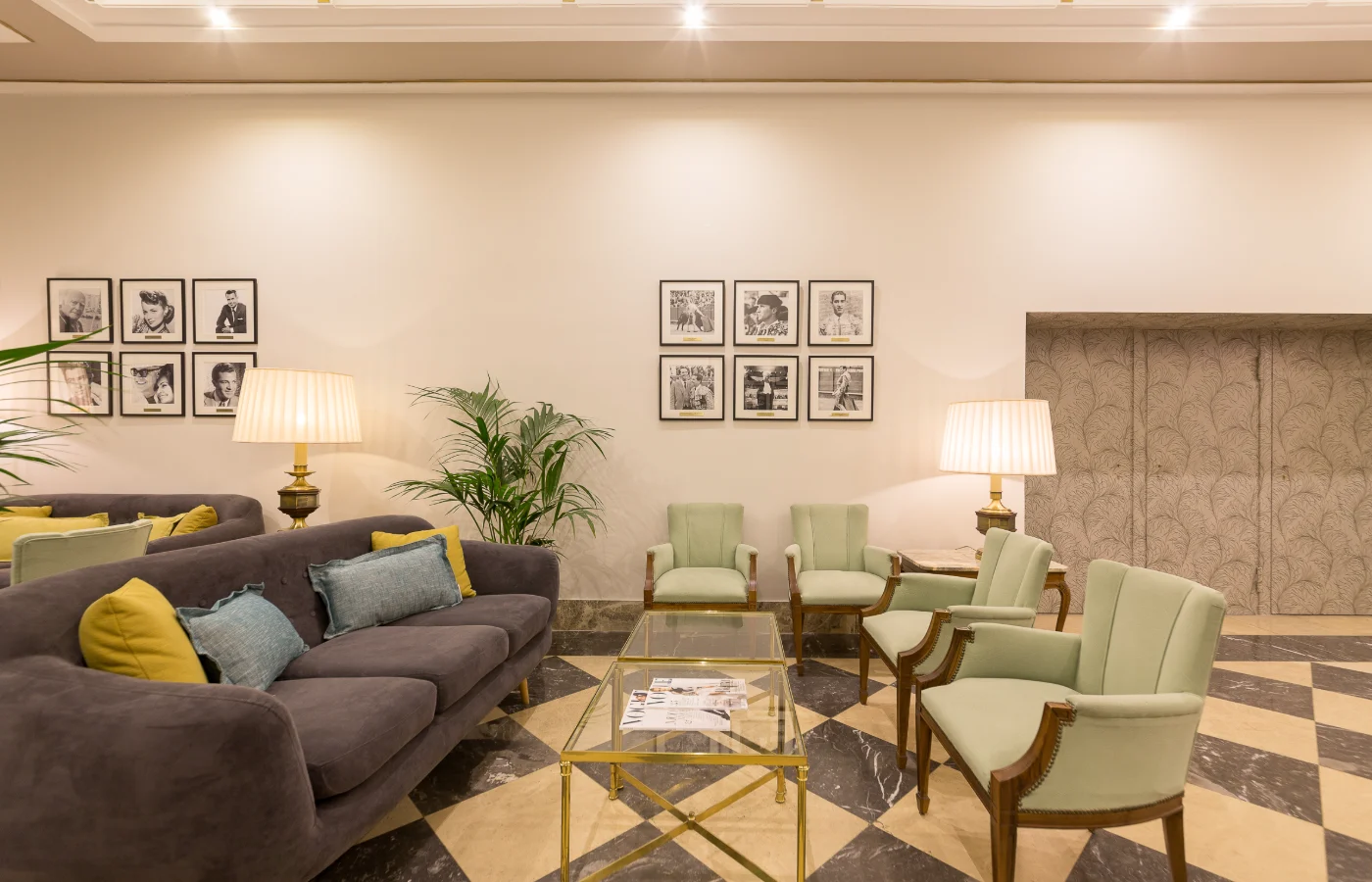 Sala de espera con sofás, sillones, mesas y lámparas junto a fotos en pared