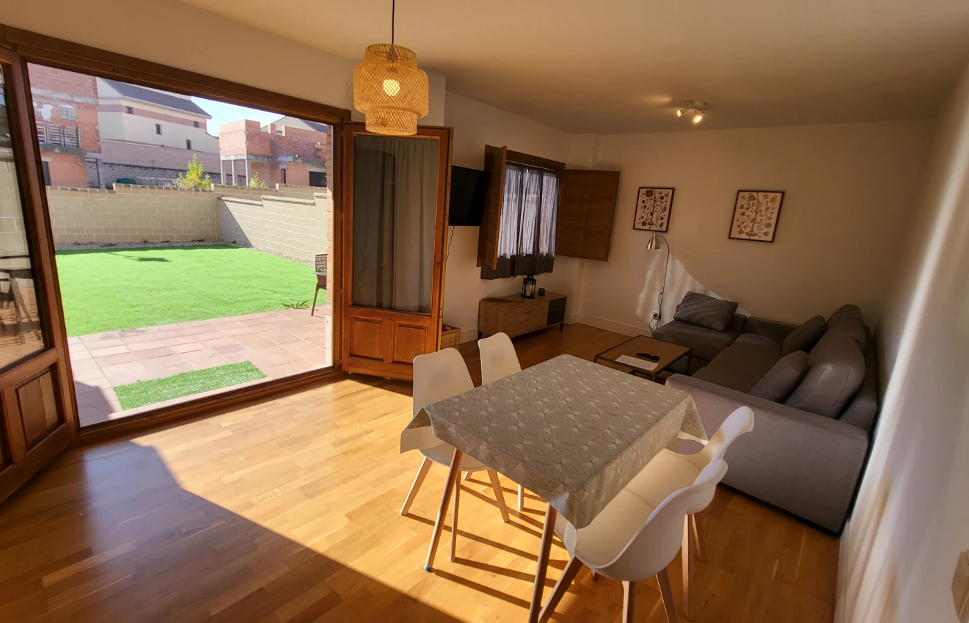 Sala comedor con sof&aacute;, mesa, sillas y salida a patio con c&eacute;sped verde