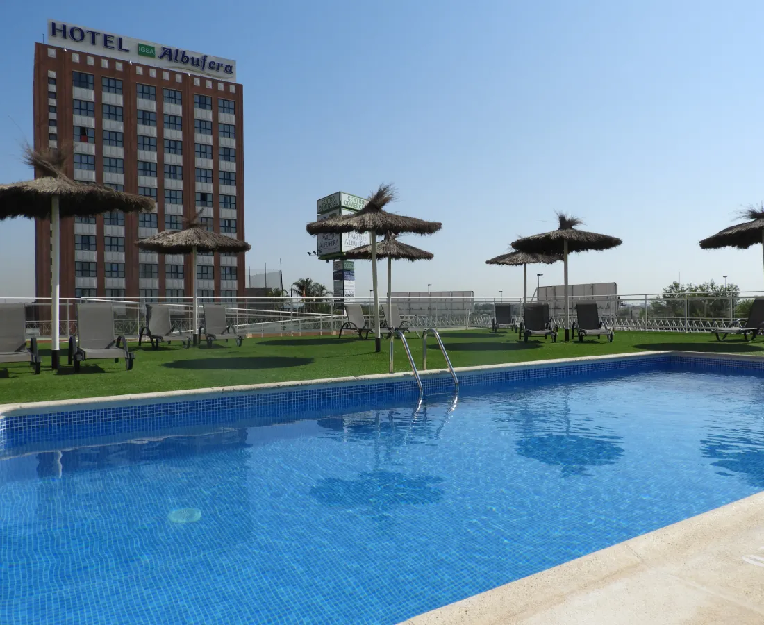 Piscina azul con tumbonas y sombrillas; edificio del Hotel Albufeira al fondo.