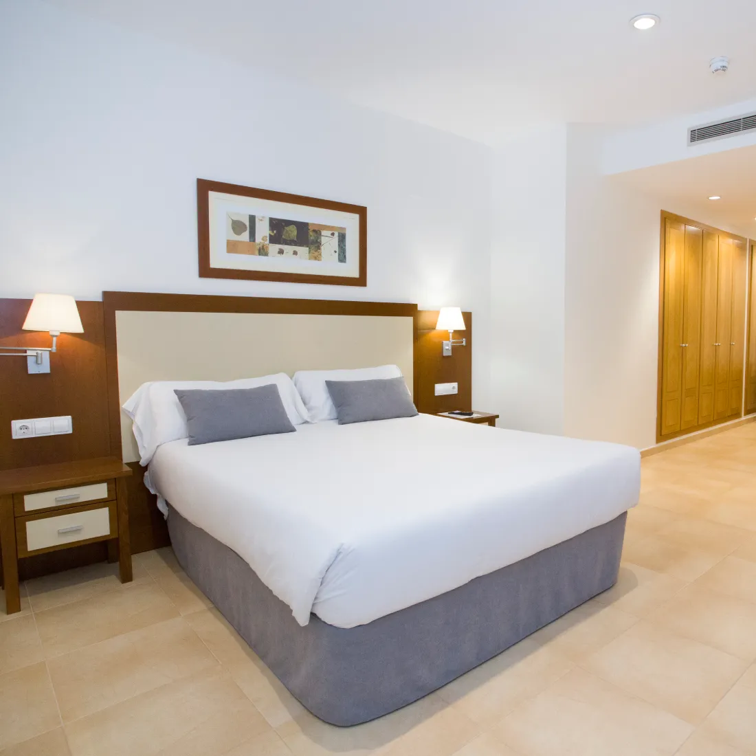 Dormitorio moderno con cama doble, l&aacute;mparas y armario de madera