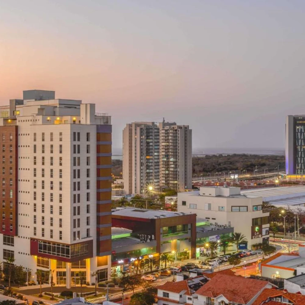 Vista urbana al atardecer con edificios altos y calles iluminadas de noche