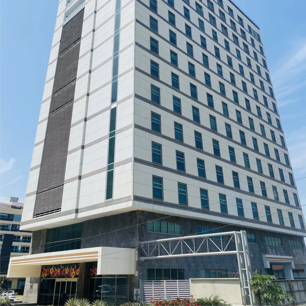 Edificio moderno de oficinas con ventanas azules y fachada blanca, al cielo.