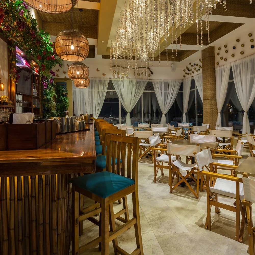 Interior de un sal&oacute;n de eventos con mesas, sillas y candelabros de luces colgantes