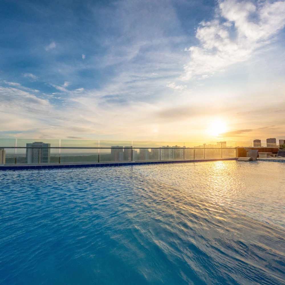 Piscina infinita con el sol al atardecer y rascacielos al fondo