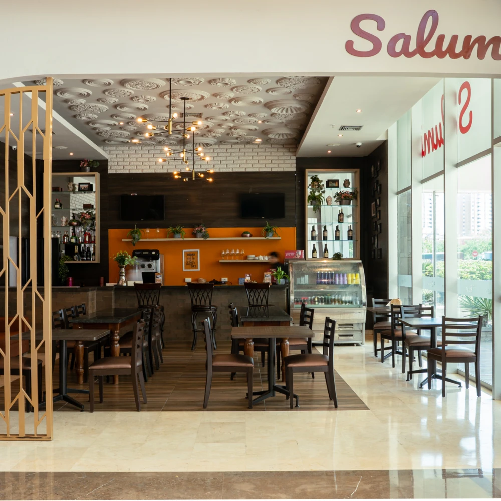 Interior de restaurante con barra, mesas y l&aacute;mparas colgantes, vista panor&aacute;mica.