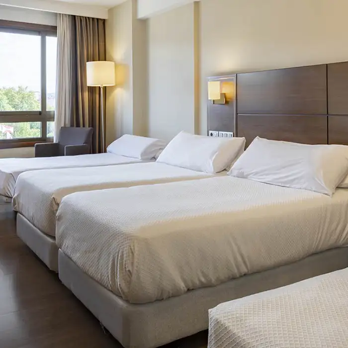 Habitaci&oacute;n de hotel moderna con cama doble y l&aacute;mparas de pie.