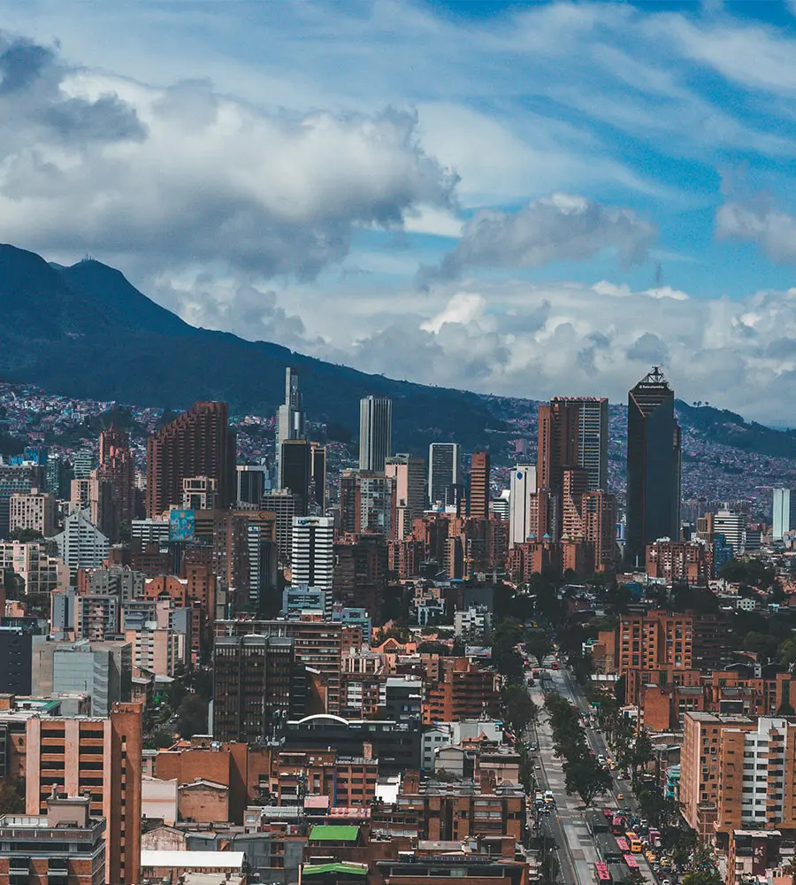 Vista urbana con rascacielos y monta&ntilde;as bajo nubes en un atardecer