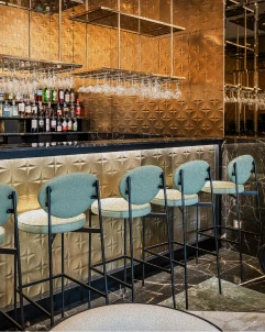 Bancos altos azuis em bar com paredes de madeira e prateleiras de bebidas