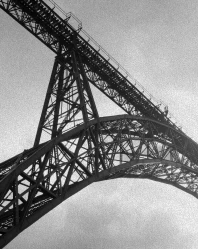 Estrutura de a&ccedil;o da ponte em vista inferior, com c&eacute;u nublado ao fundo
