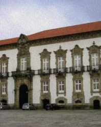 Fachada de pr&eacute;dio hist&oacute;rico com janelas e jardim frontal, em tons claros