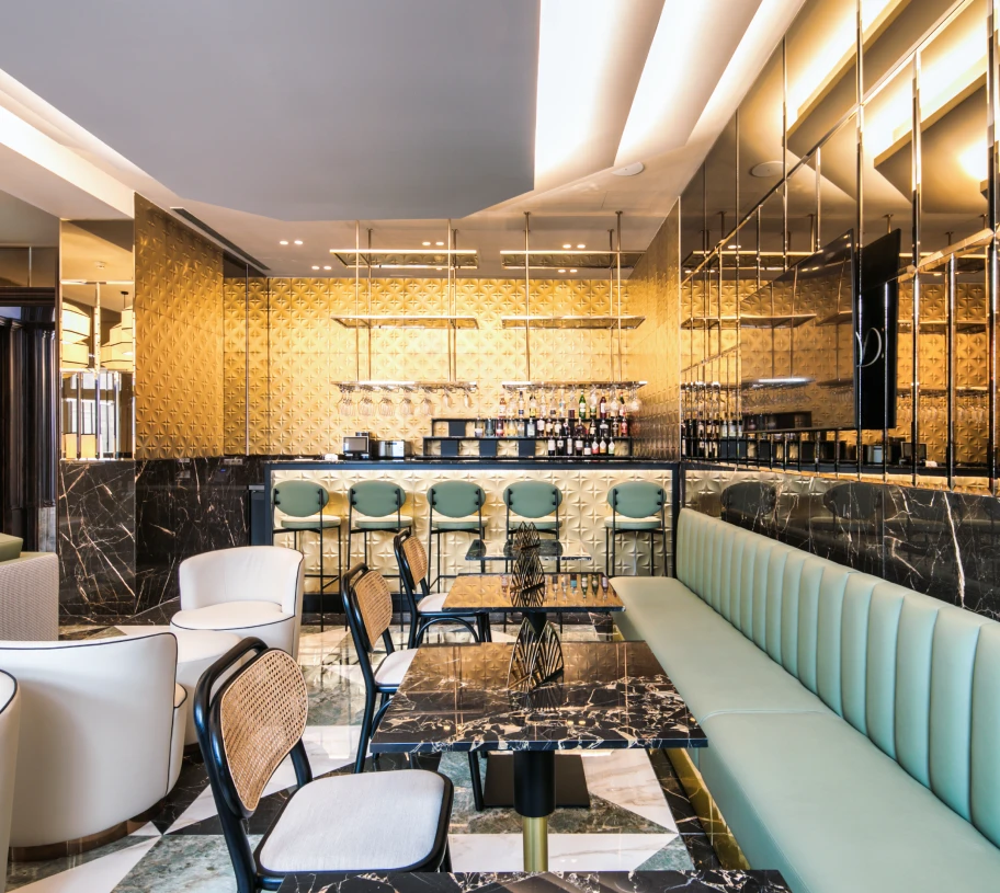 Ambiente interno moderno com bar, bancos e mesas de jantar em hotel.