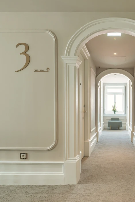 Corredor de hotel com n&uacute;mero 3 e arcos brancos