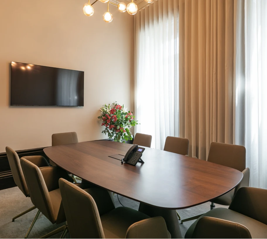 Sala de reuni&otilde;es moderna com mesa de madeira, cadeiras e flores ao centro