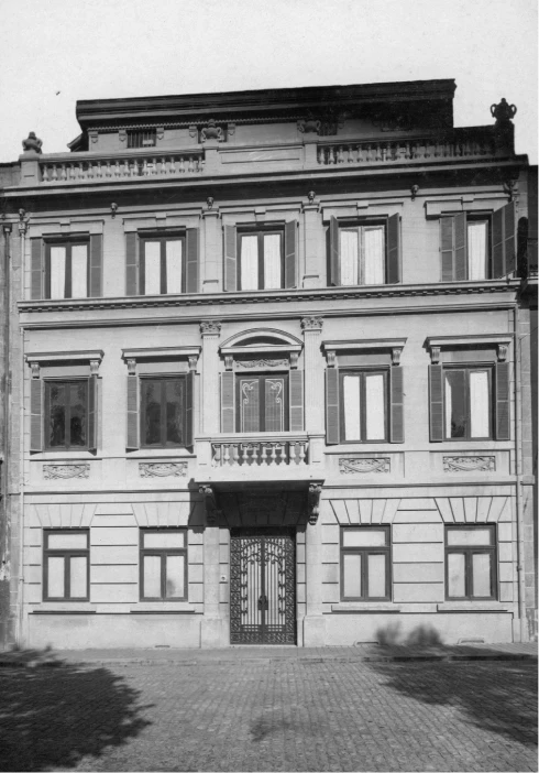 Fachada de pr&eacute;dio antigo com janelas e port&atilde;o central.