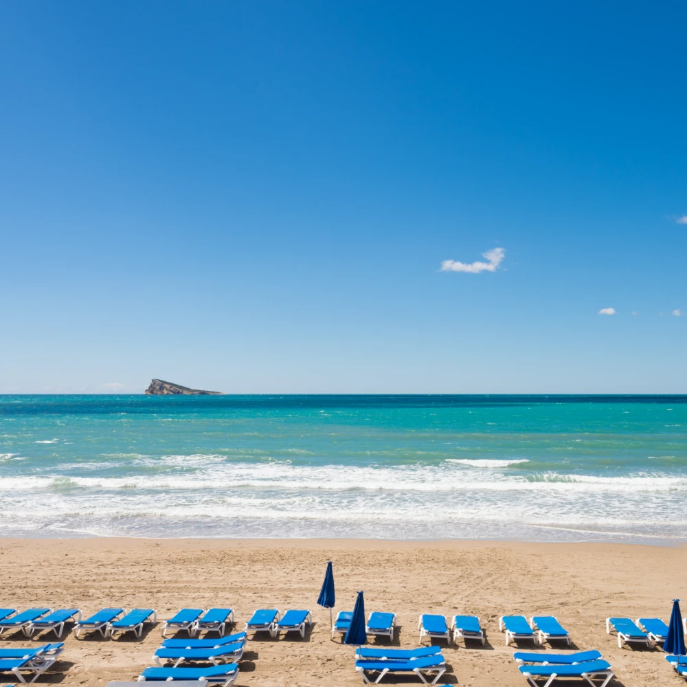 El mar azul con el cielo despejado, en la arena et&aacute;n colocadas unas 15 hamacas.