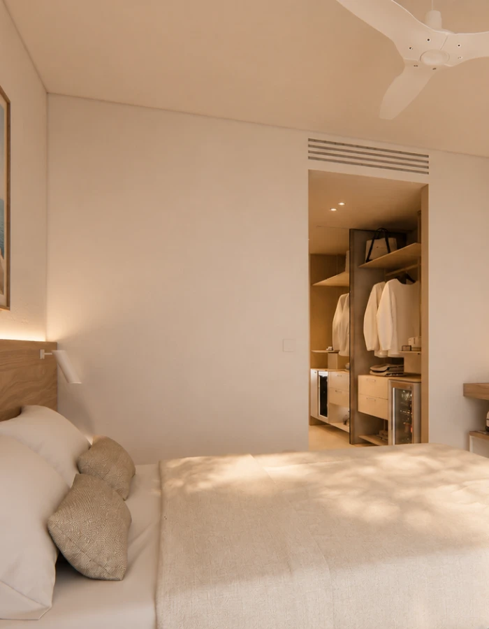 Dormitorio minimalista con cama y armario abierto, luz c&aacute;lida y ventilador.
