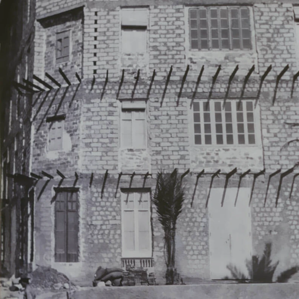 Patio interior con edificio de ladrillo y rejas de hierro, estilo antiguo, en blanco y negro